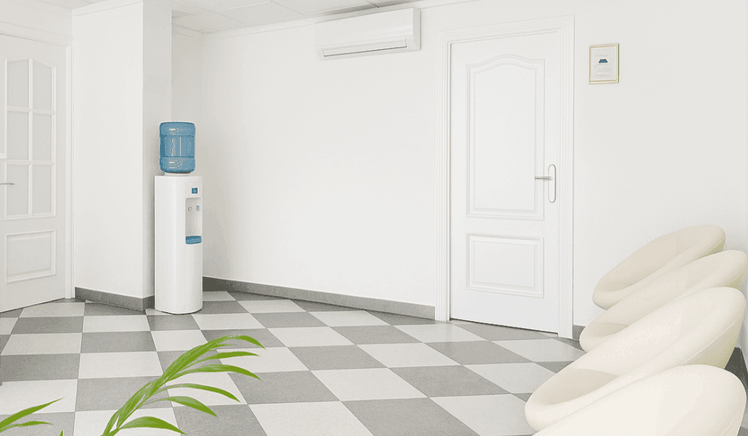 Sala de espera en Clínica Dental RM en Montequinto, con dispensador de agua, sillas blancas y ambiente minimalista.