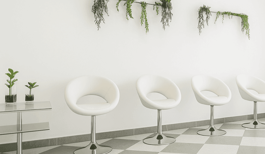 Sala de espera moderna en Clínica Dental RM en Montequinto, Dos Hermanas, con sillas blancas y decoración con plantas.